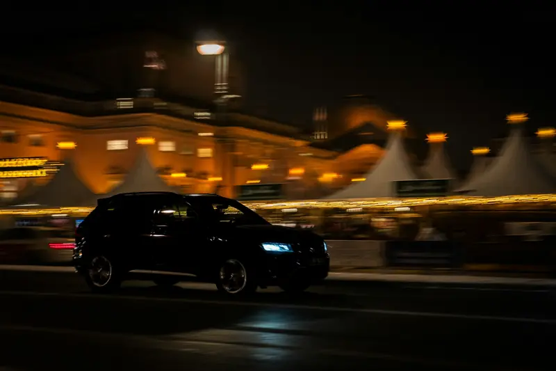 Zwarte SUV rijdt 's avonds door een verlichte stad
